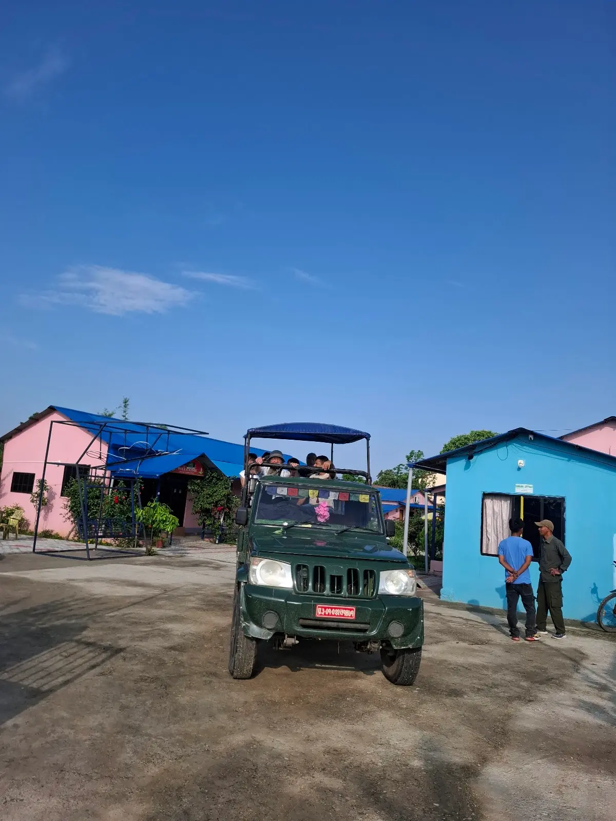A safari jeep parked between the cottages, ready to take guests into the park